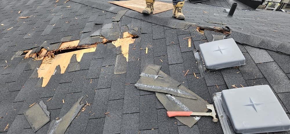 Close-up of lightning strike impact — exposed plywood decking, shingles displaced — Pickering townhome