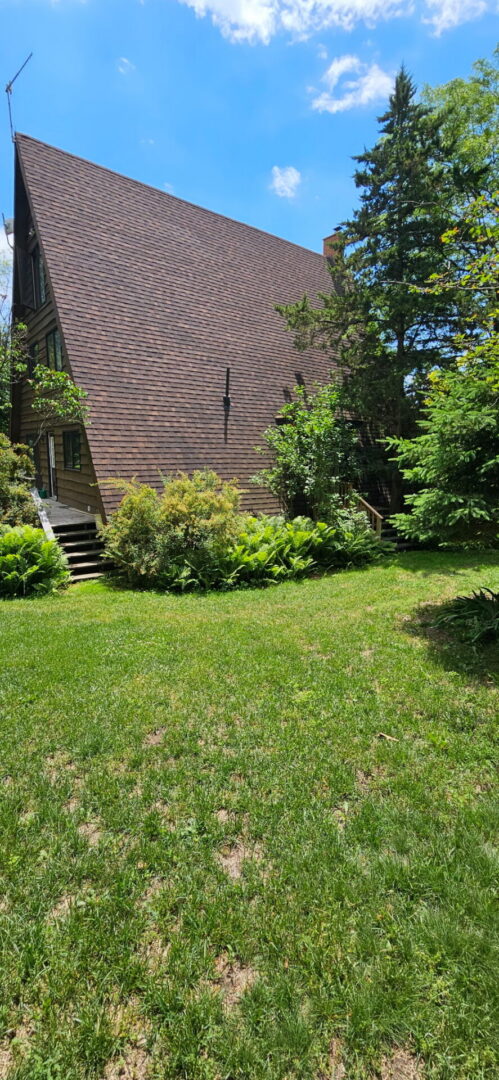 Steep side slope of a Claremont A-frame cottage re-shingled with new architectural asphalt shingles