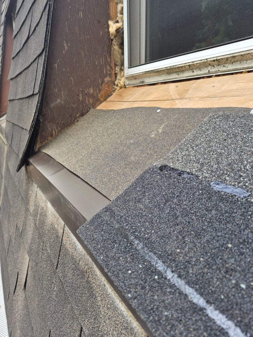 New underlayment and new asphalt shingles being installed below a repaired roof window in Ajax